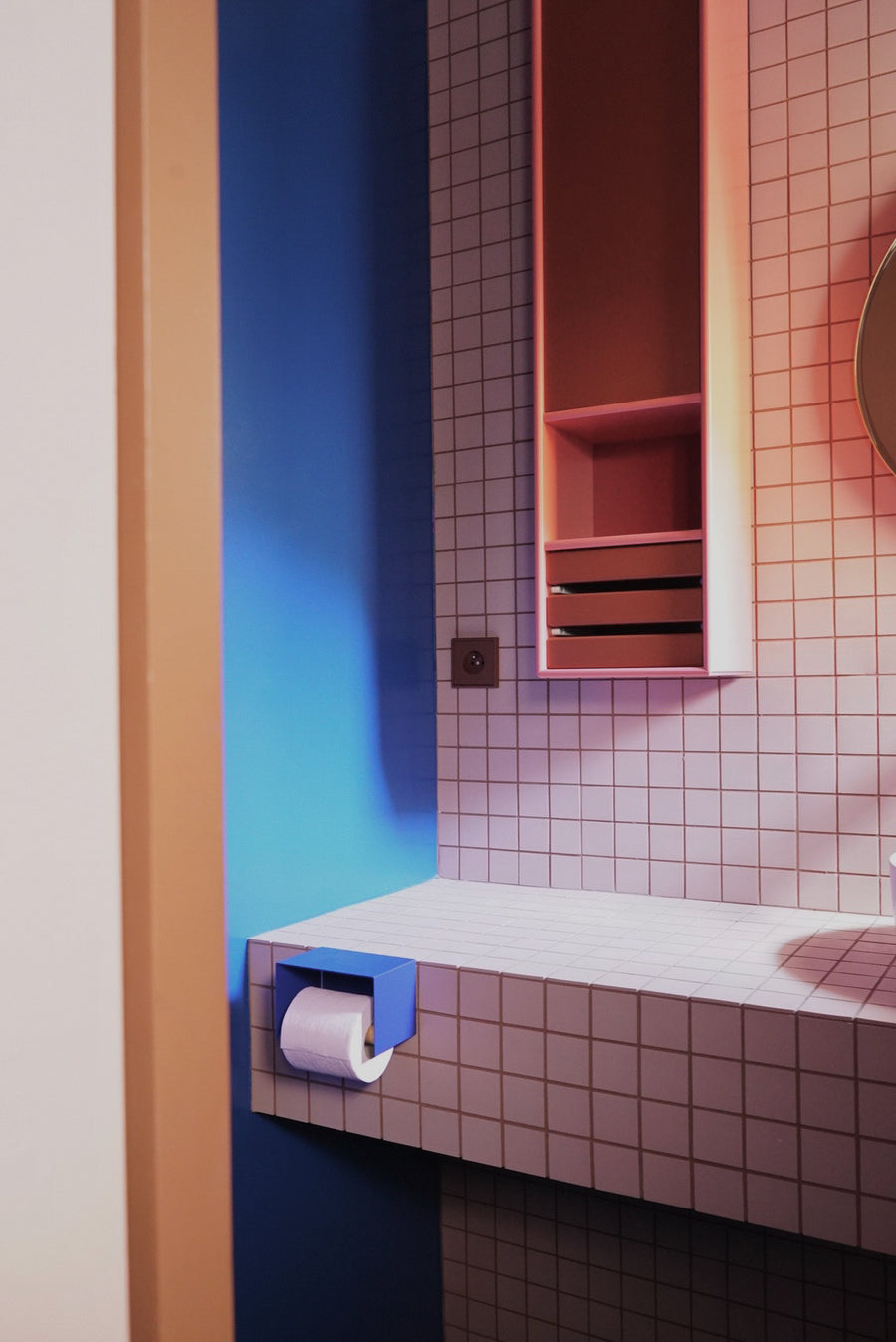 blue toilet paper holder in nice design where you can put things on top like a phone or candle or some small accessories. Here shown in an actual bathroom