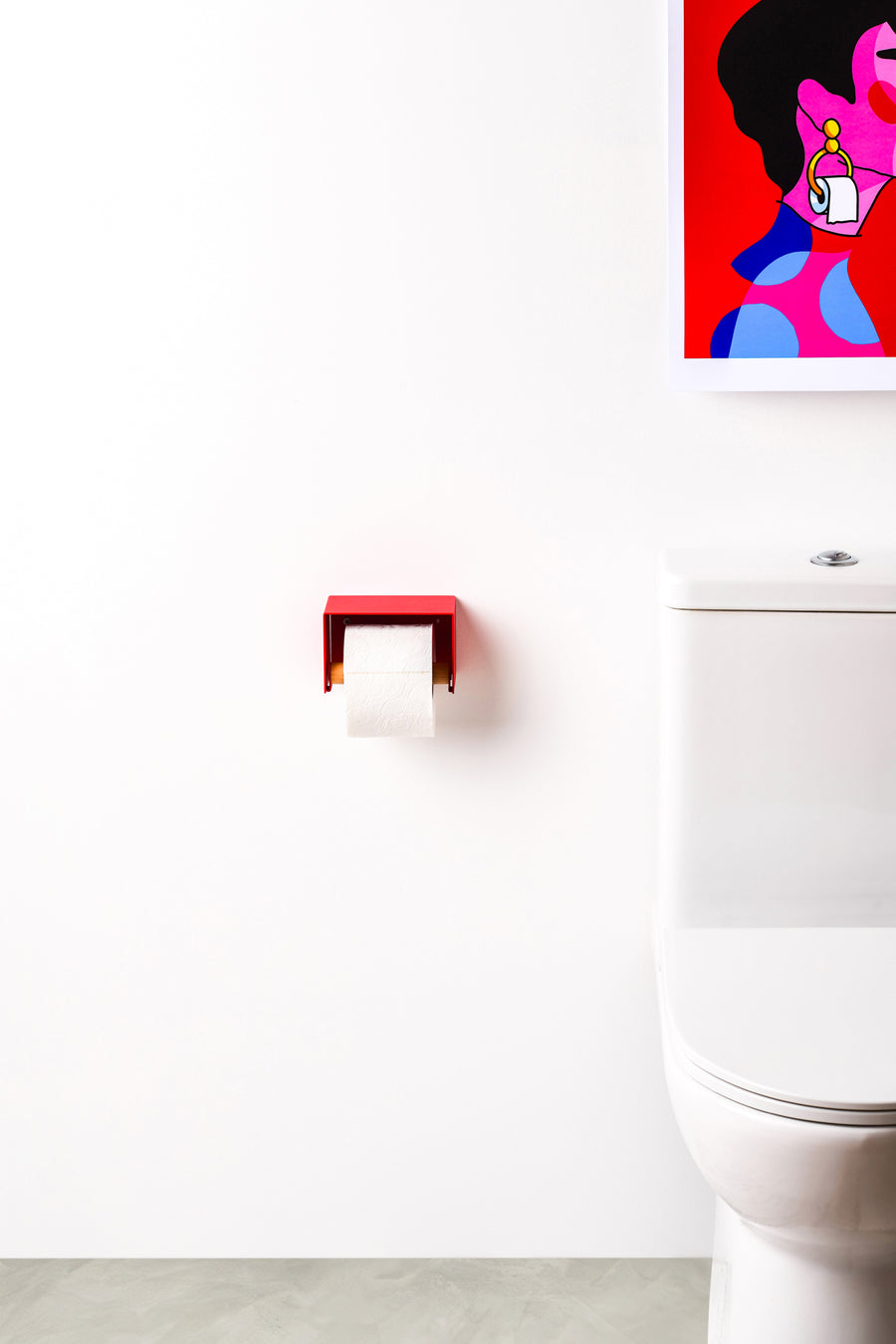 red toilet paper holder in nice design where you can put things on top like a phone or candle or some small accessories. Here shown hanging next to an actual toilet
