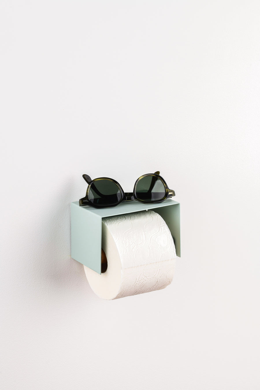 sage green toilet paper holder in nice design where you can put things on top like a phone or candle or some small accessories.  With sunglass on top
