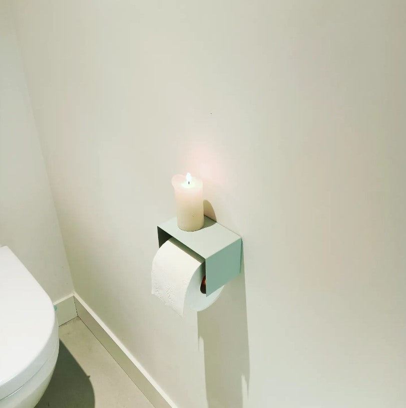 sage green toilet paper holder in nice design where you can put things on top like a phone or candle or some small accessories.  Here displayed with a candle on top in actual toilet