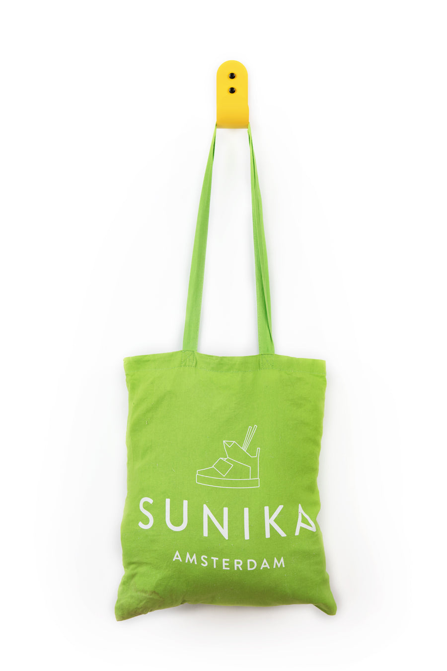green tote bag hanging on yellow wall hook with black screws