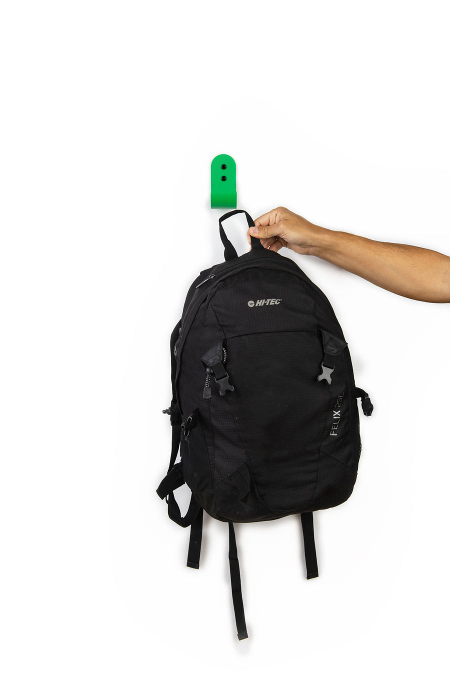 hand taking a black backpack from a green wallhook