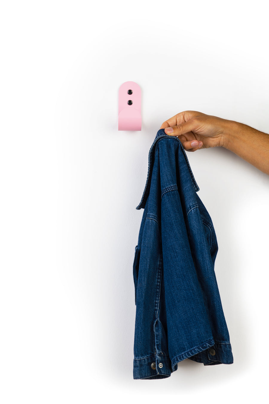 pink wall hook with hand taking off a blue denim kids jacket