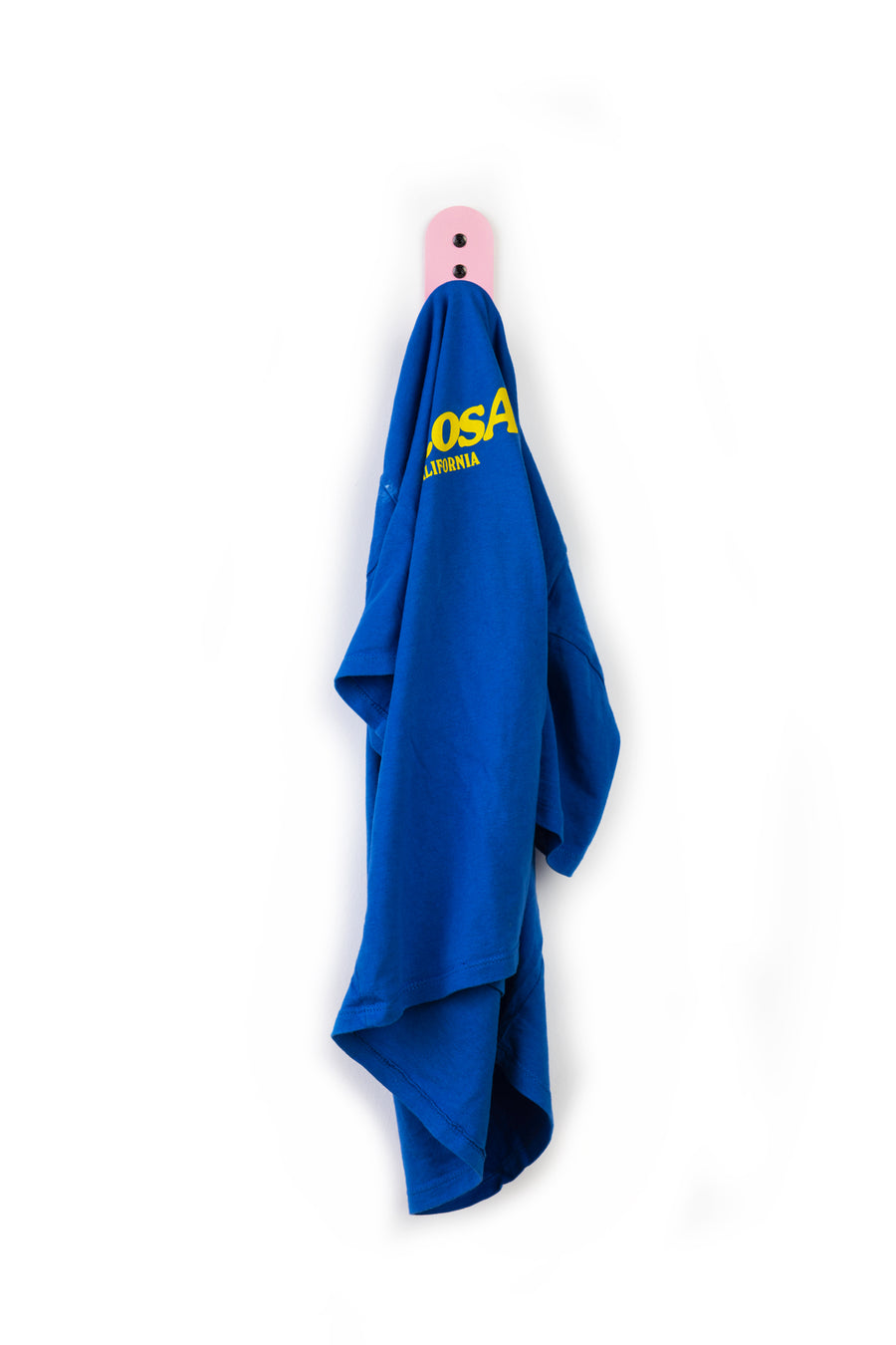 blue t-shirt with yellow letters on a pink wall hook