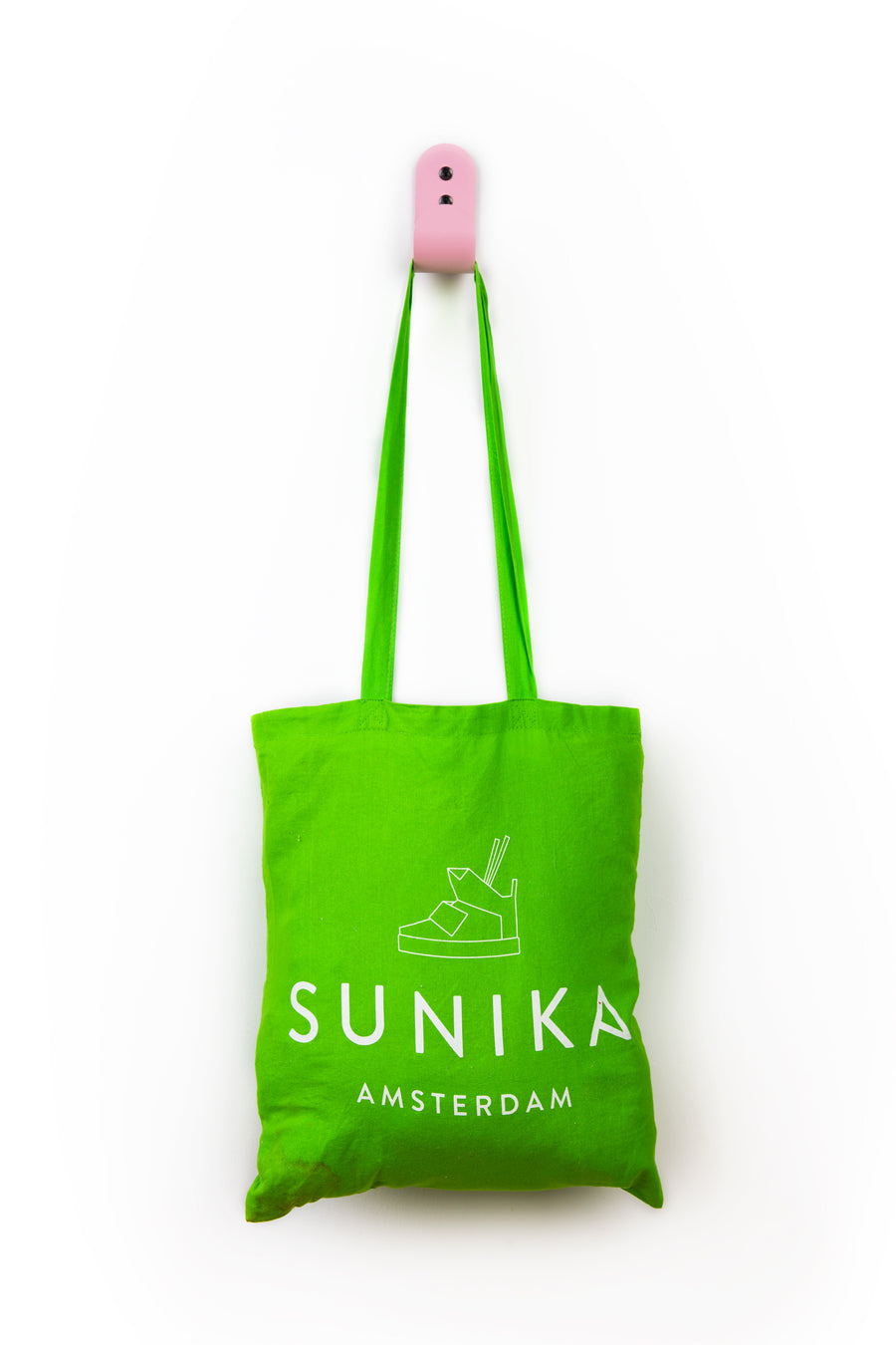 green tote bag hanging on pink wall hook
