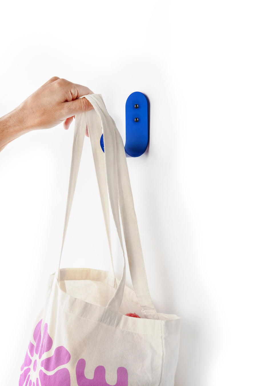 hand grabbing a tote bag from a blue large wall hook